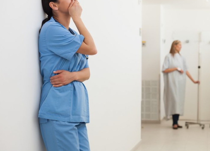 Nursing errors: nurse in scrubs upset with hand on mouth 700 x 503