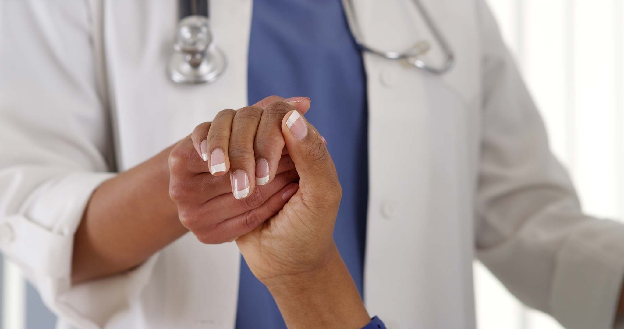 black doctor holding black patient's hand 2048 x 1080