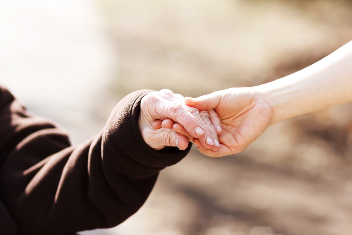 senior holding hands with carer 1500 x 1000
