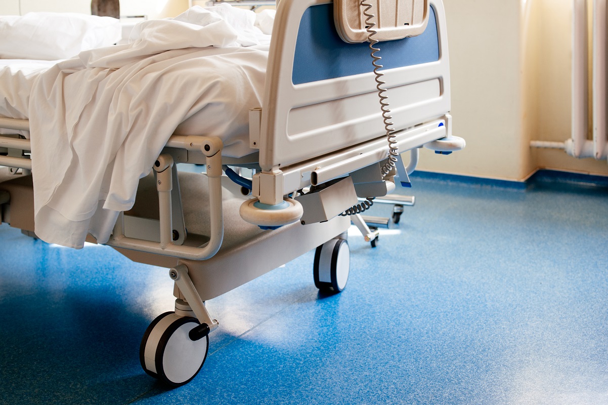 Empty modern hospital bed in a sunny room with a clean blue floor 1202 x 800