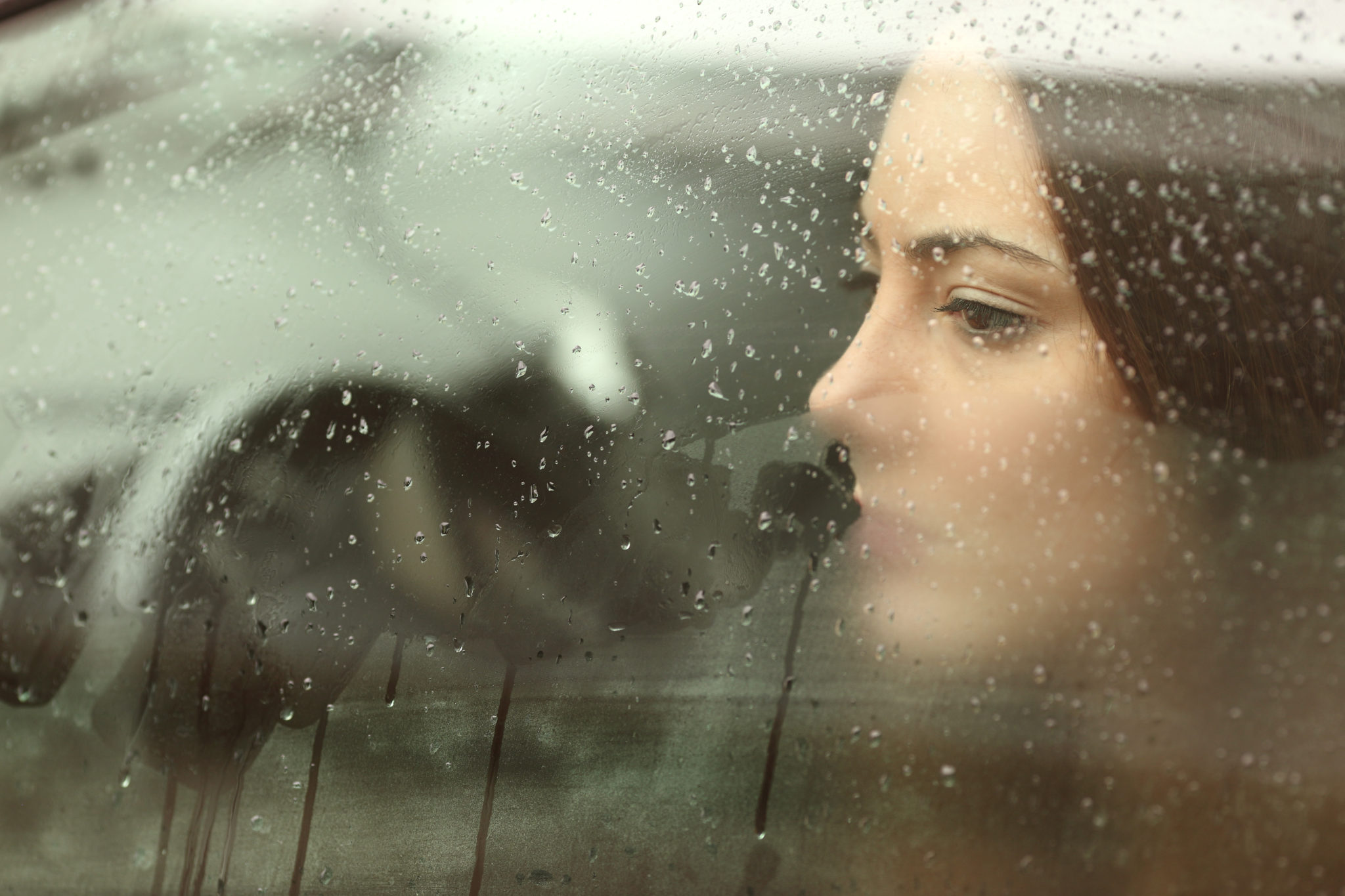 Sad woman looking through a steamy car window 2048 x 1365