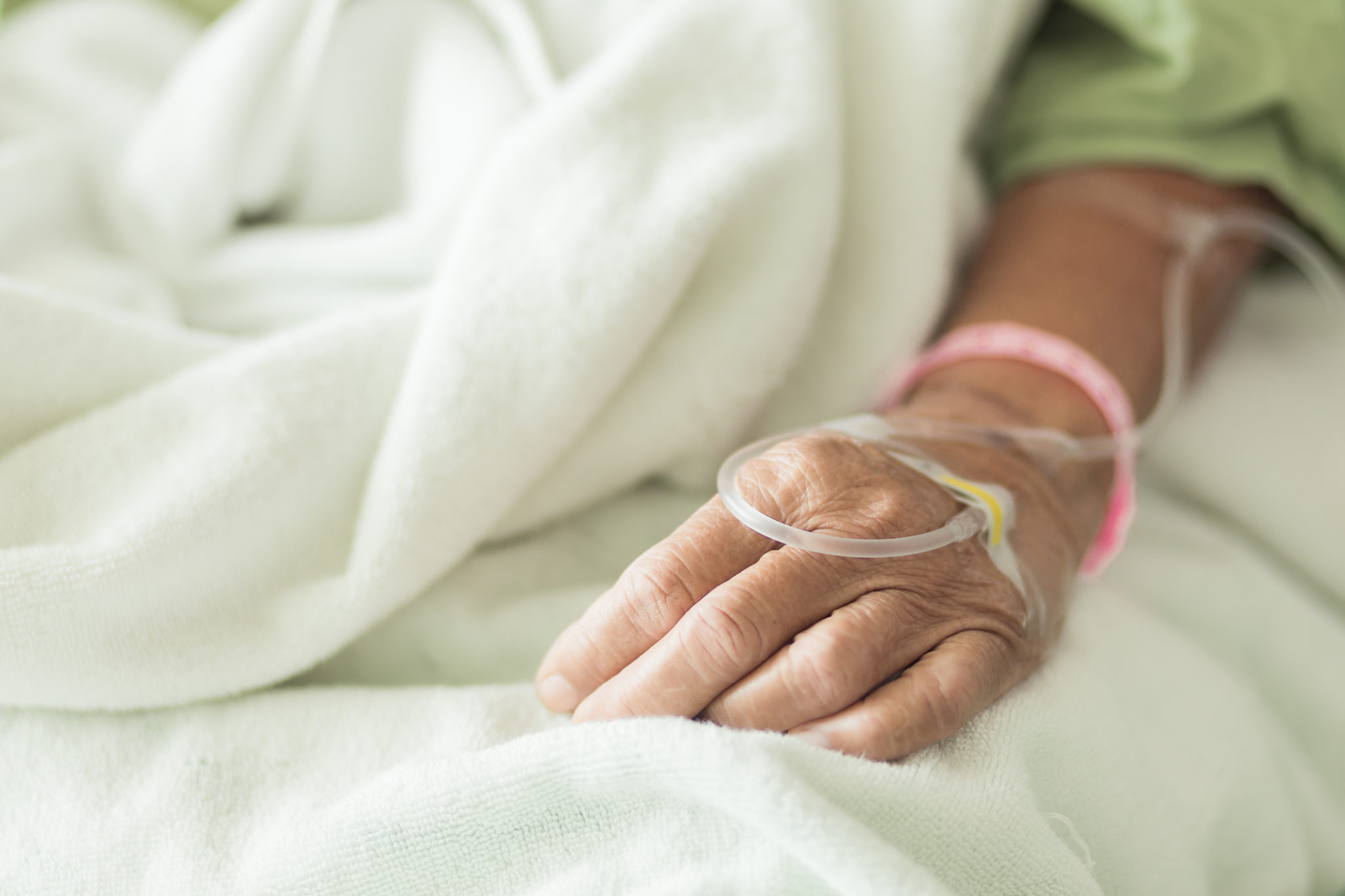Hand of old woman lying on the bed with IV line 2048 x 1365