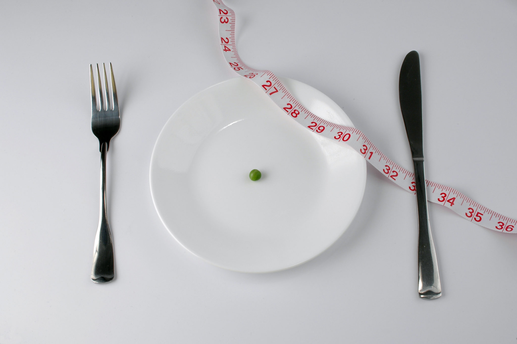 Extreme diet-empty plate except for a pea and tape measure 2048 x 1362
