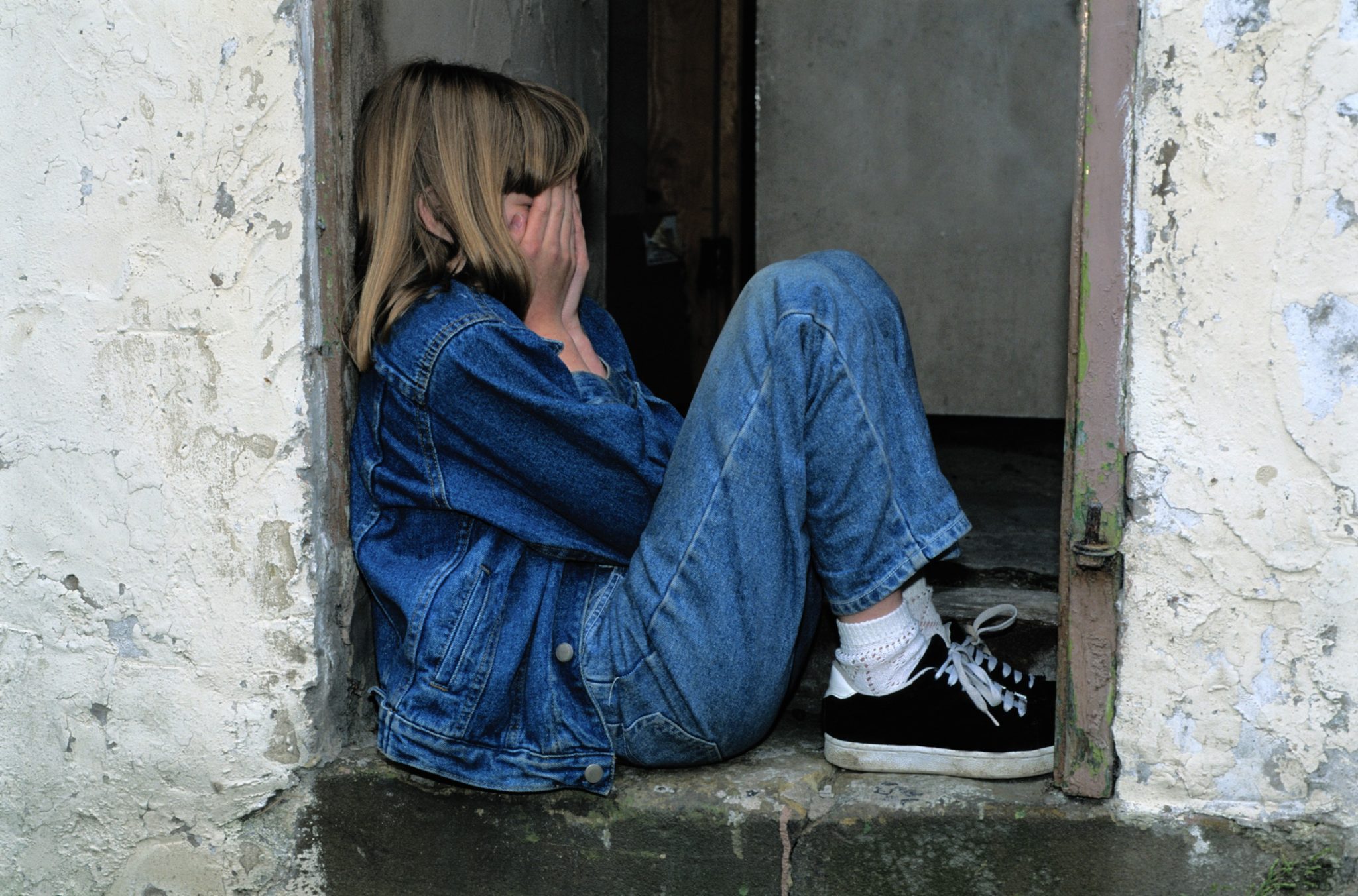 child with hands on face sitting in doorway 2048 x 1352
