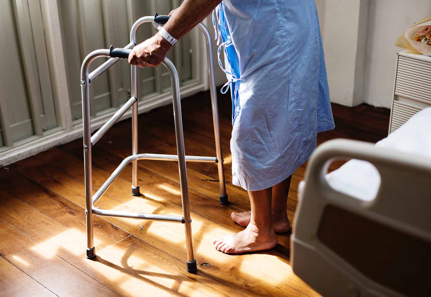 Elder person in hospital gown with walker 1500 x 1033