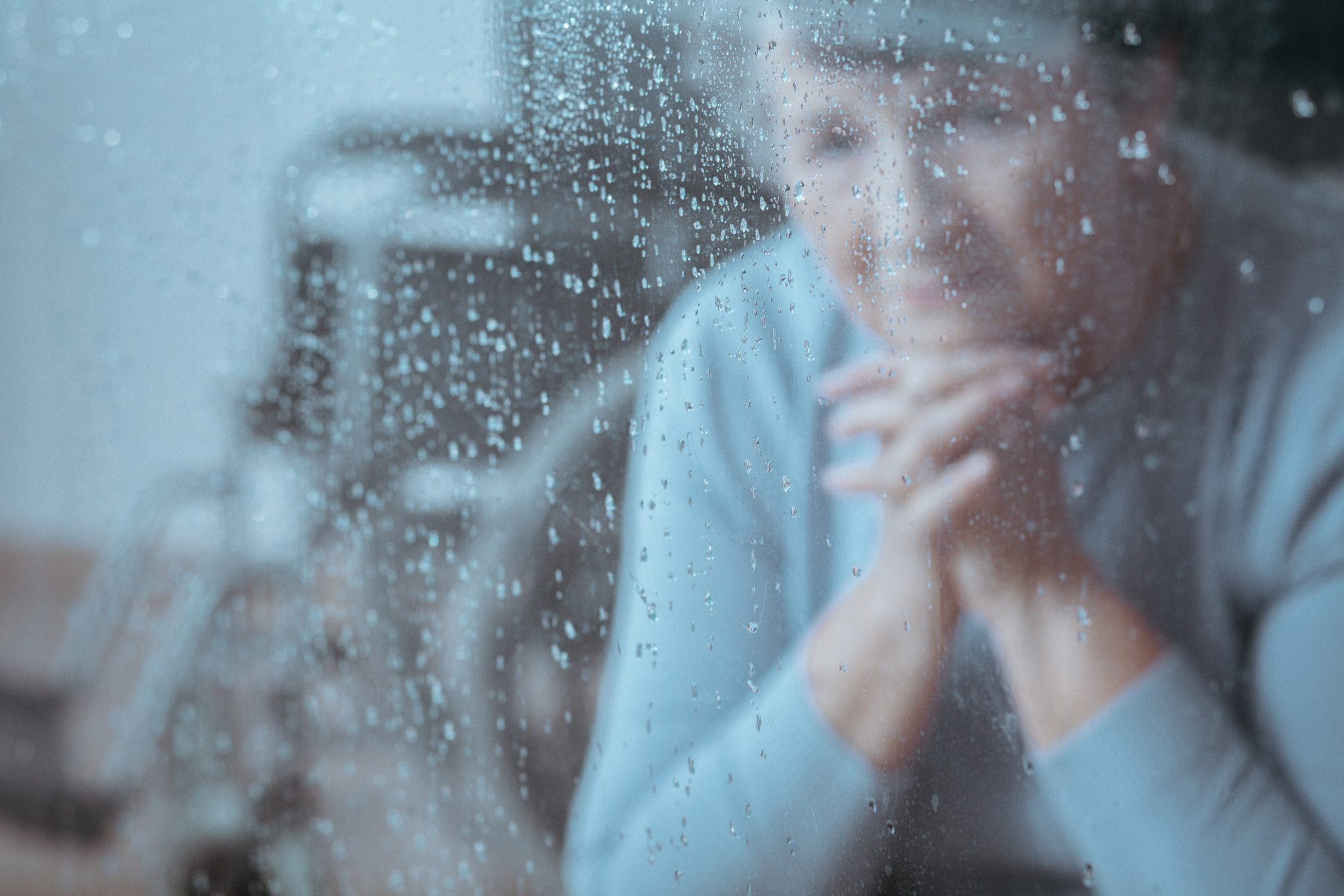 Elderly-woman-sitting-in-front-of-window-with-rainddrops 2125 x 1365