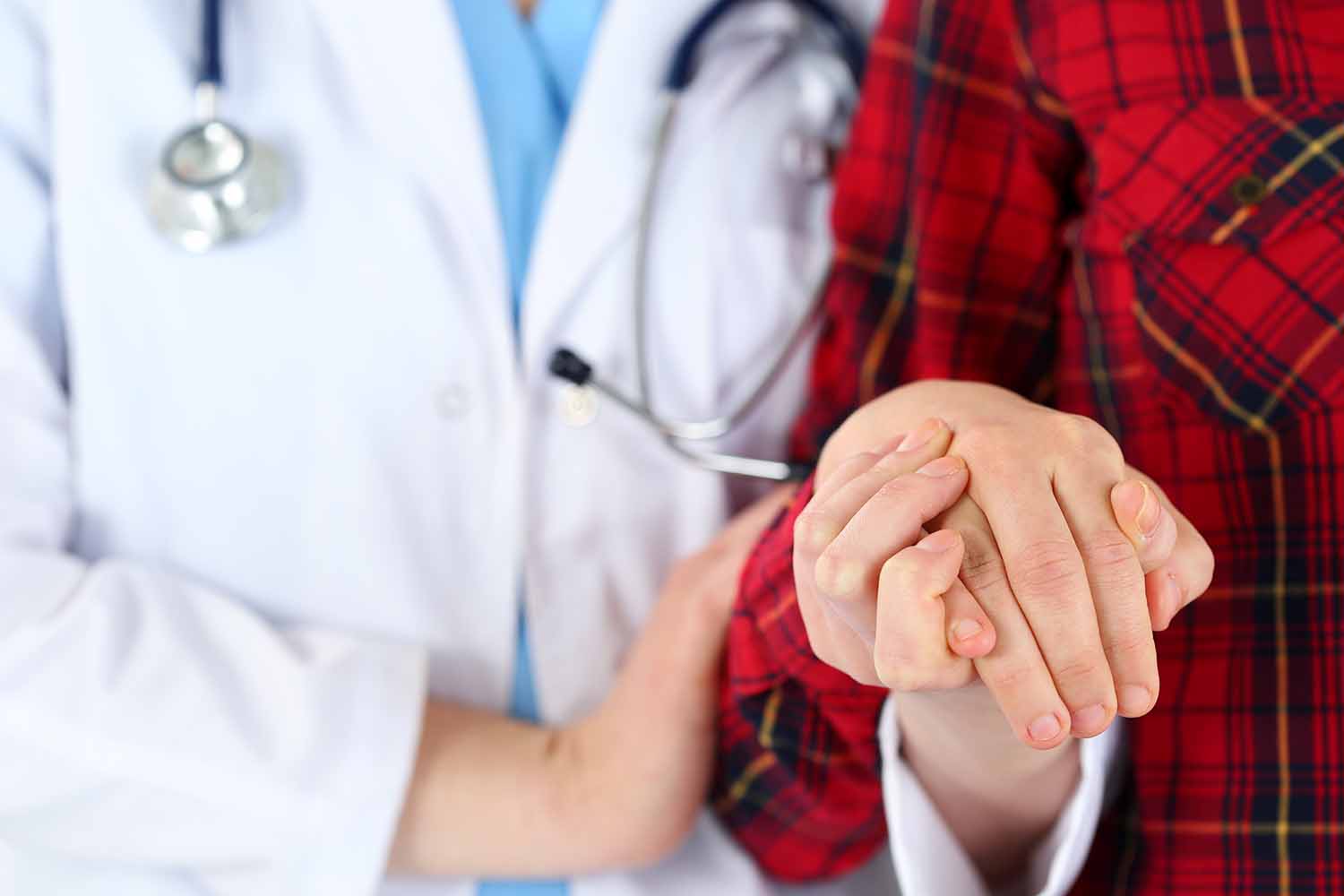 Female doctor holding elderly person in plaid robe hand 1500 x 1000