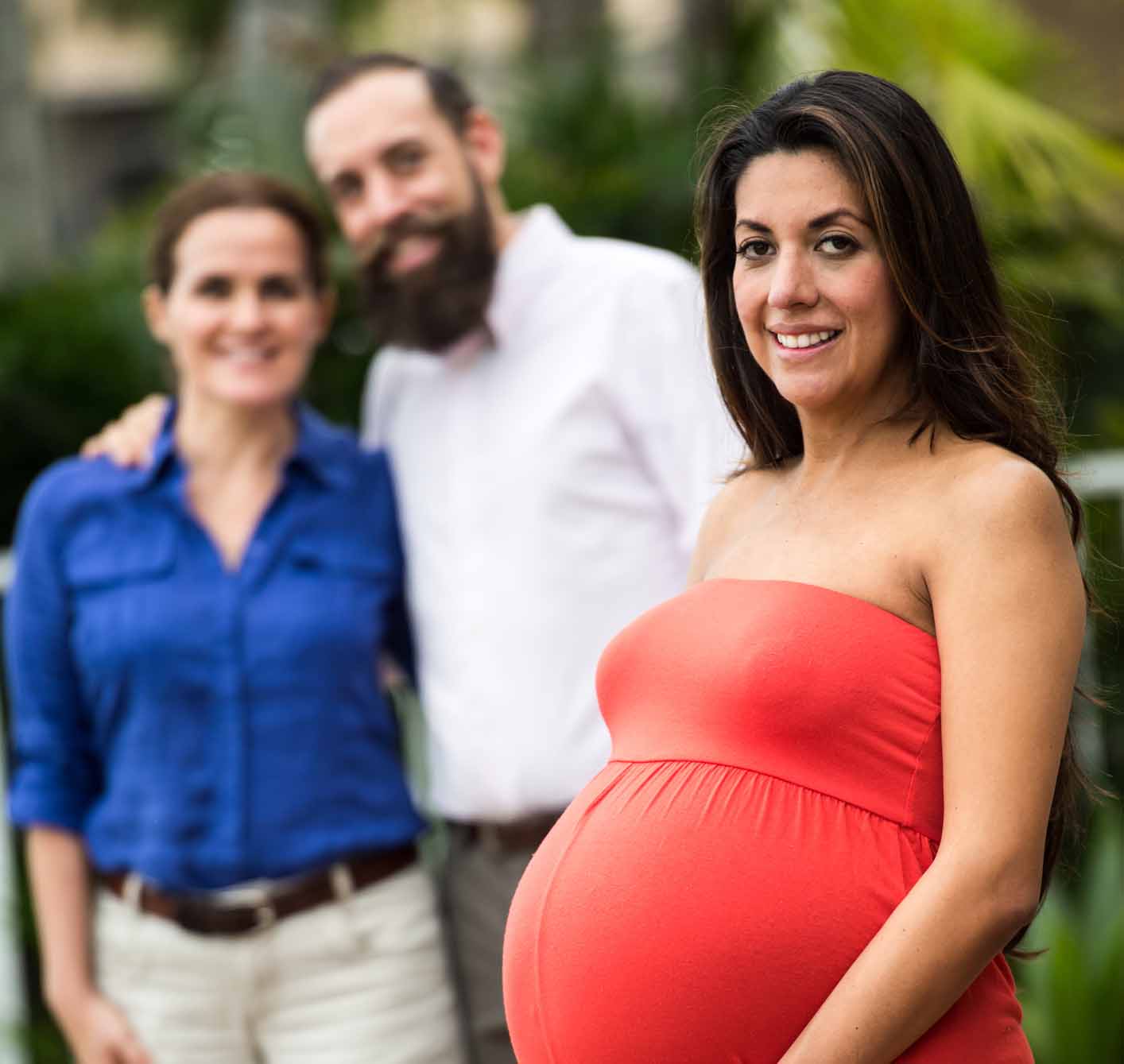 Pregnant Hispanic surrogate mother posing with the babies future parents 1414 x 1339