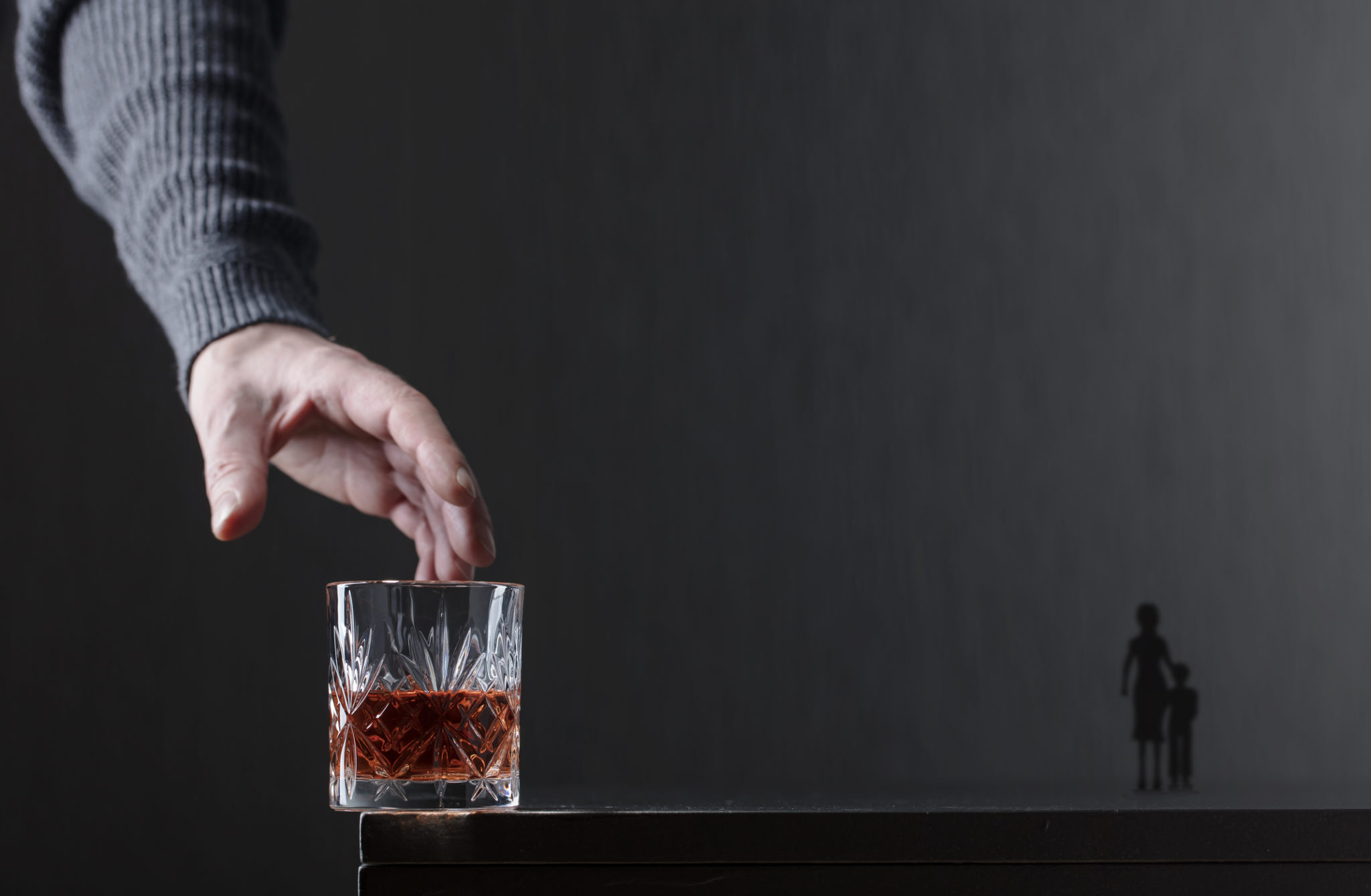 Man's hand reaching for glass of whisky (alcoholic spouse)
