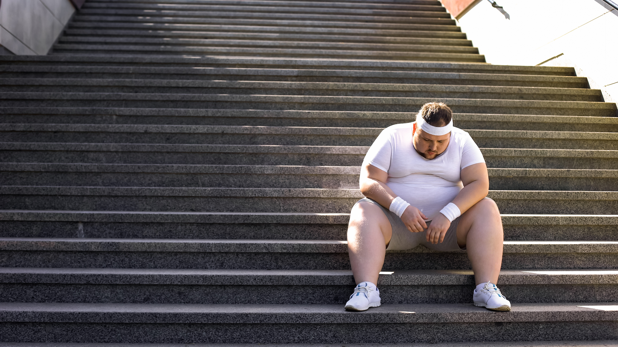 obese man sitting on stairs 2000 x 1125