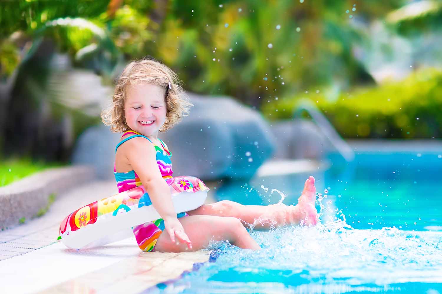 Cute little girl splashing in swimming pool 1500 x 1000